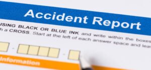 Close-up of an accident report form, emphasizing the title and instructions for filling it out, with a pen ready to write.